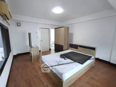 Spacious bedroom with modern wooden furniture and ample natural light.