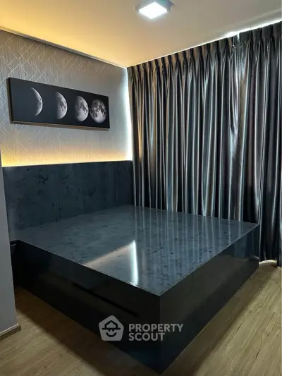 Modern bedroom with sleek black bed and moon phase artwork, featuring elegant curtains and wooden flooring.
