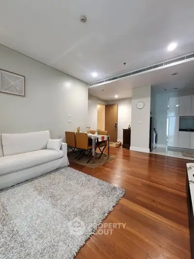 Modern living room with hardwood floors, cozy seating, and dining area in open layout apartment.