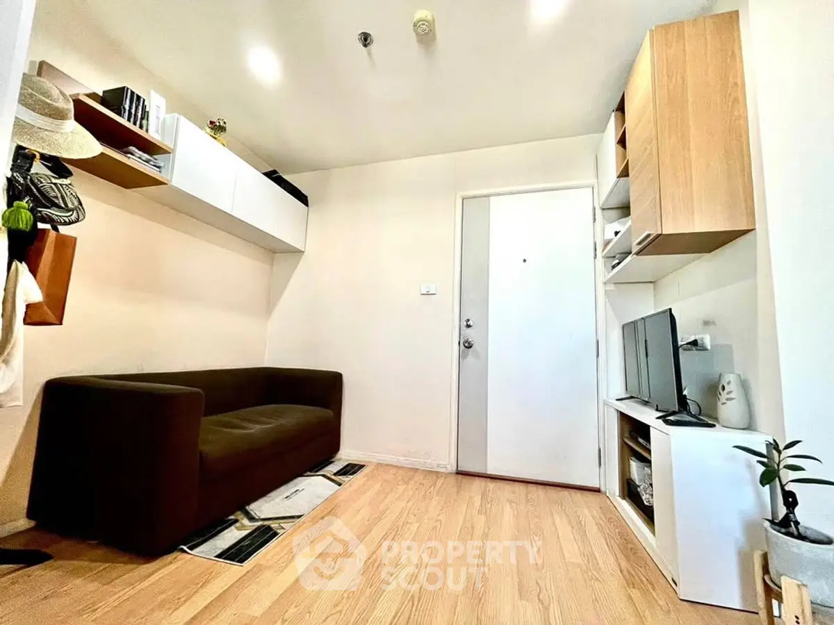 Modern living room with sleek furniture and wooden flooring, featuring a cozy sofa and built-in storage.