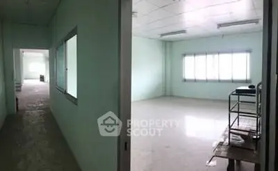 Spacious empty room with large windows and hallway in commercial building.