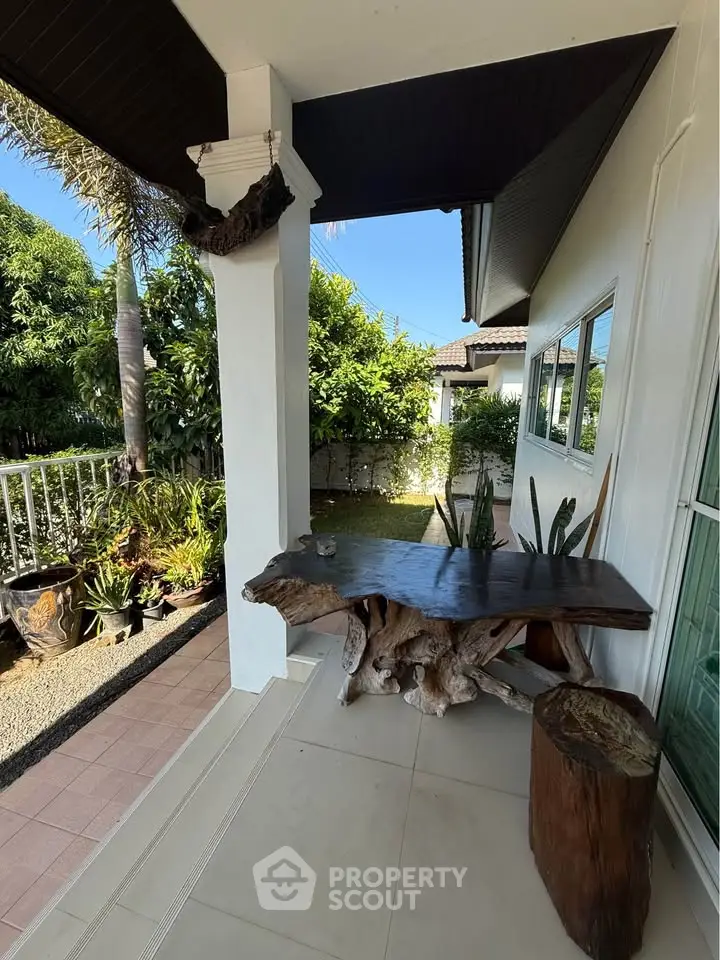 Charming outdoor patio with rustic wooden table and lush garden view, perfect for relaxation and entertaining.