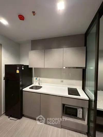 Modern compact kitchen with sleek cabinetry and built-in appliances in a stylish apartment.