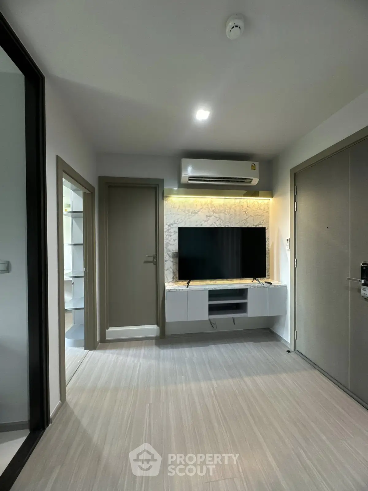 Modern living room with sleek TV setup and air conditioning in a stylish apartment.