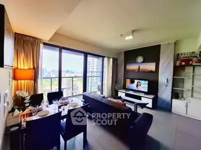 Modern living room with dining area and city view, featuring sleek furniture and large windows.