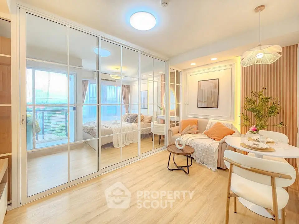 Bright and modern living room with mirrored closet doors and cozy dining area in a stylish apartment.