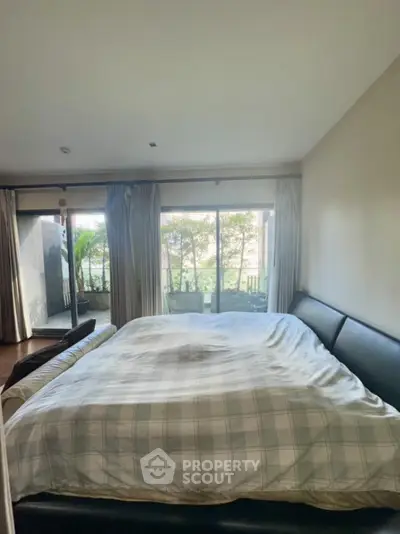 Spacious bedroom with large windows and garden view, perfect for relaxation and comfort.