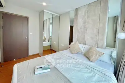 Modern bedroom with stylish decor and mirrored wardrobe in a cozy apartment.