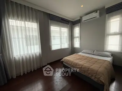 Spacious bedroom with large windows and modern air conditioning unit, offering ample natural light and comfort.