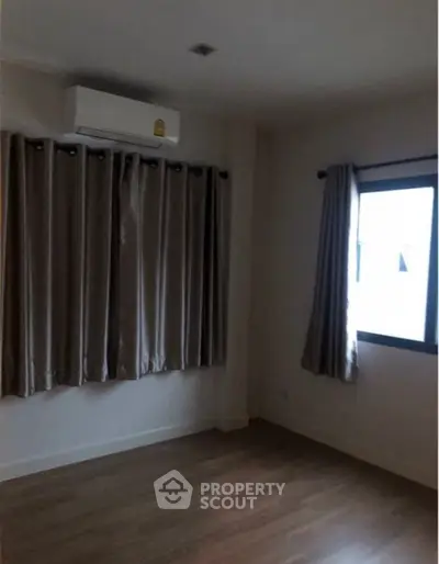 Cozy and well-lit bedroom with elegant curtains and air conditioning, perfect for comfortable urban living.
