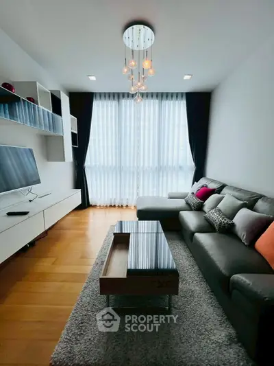 Modern living room with stylish decor, large window, and comfortable seating in a cozy apartment.