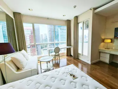 Luxurious bedroom with city view, elegant furnishings, and natural light in modern high-rise apartment.