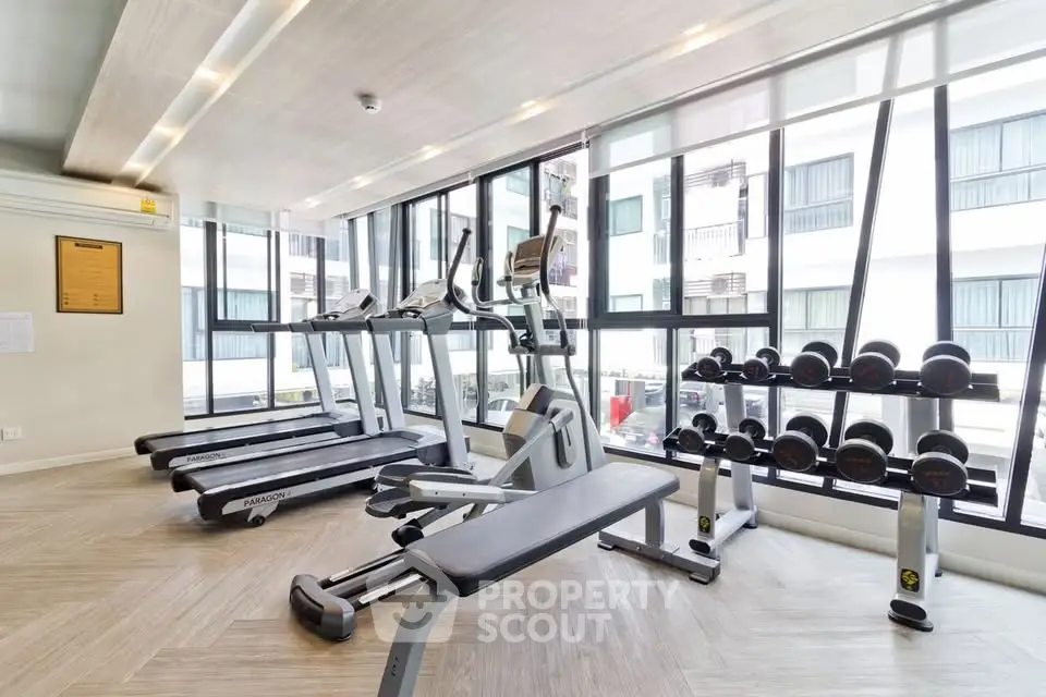 Modern gym with state-of-the-art equipment and large windows in a luxury apartment building.