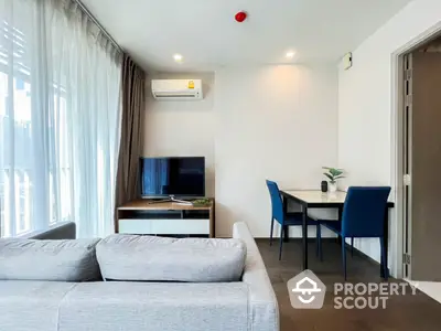 Modern living room with cozy sofa, TV, and dining area in a bright apartment.