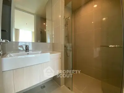Modern bathroom with sleek glass shower and stylish sink in a contemporary apartment.