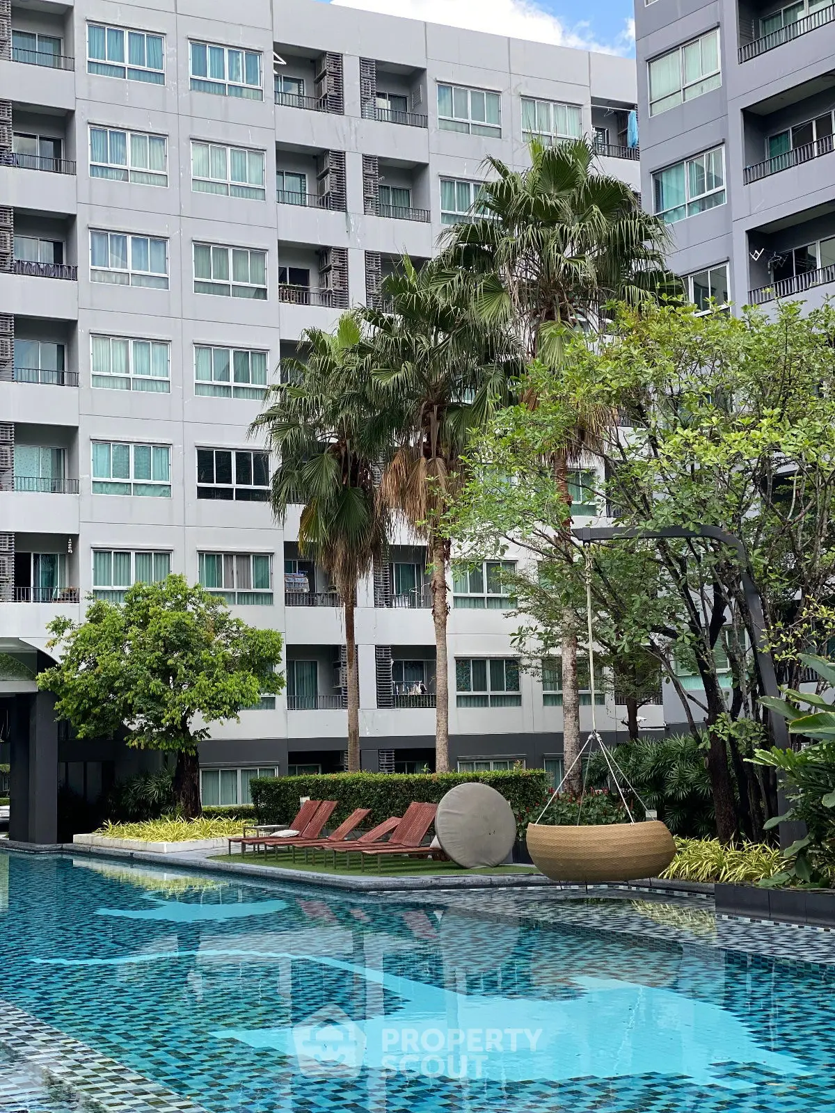 Luxurious apartment complex with a stunning pool and lush greenery, perfect for modern living.