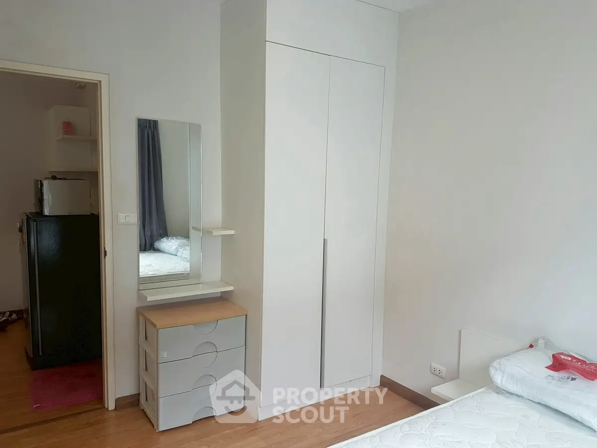 Cozy bedroom with modern wardrobe and dresser, perfect for urban living.