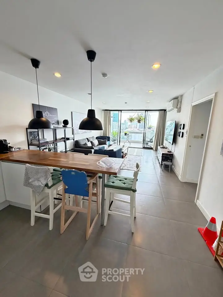 Spacious modern living room with open kitchen and large windows offering natural light and garden view.