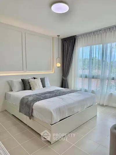 Modern bedroom with elegant decor and large windows offering natural light.