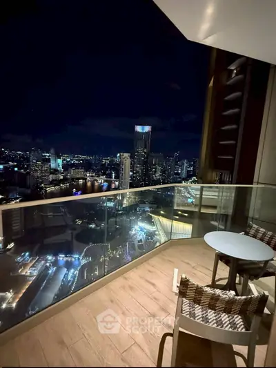 Stunning night city view from a modern high-rise balcony with cozy seating.