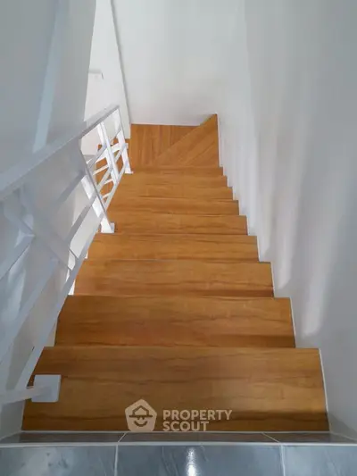 Modern wooden staircase with sleek white railing in a contemporary home