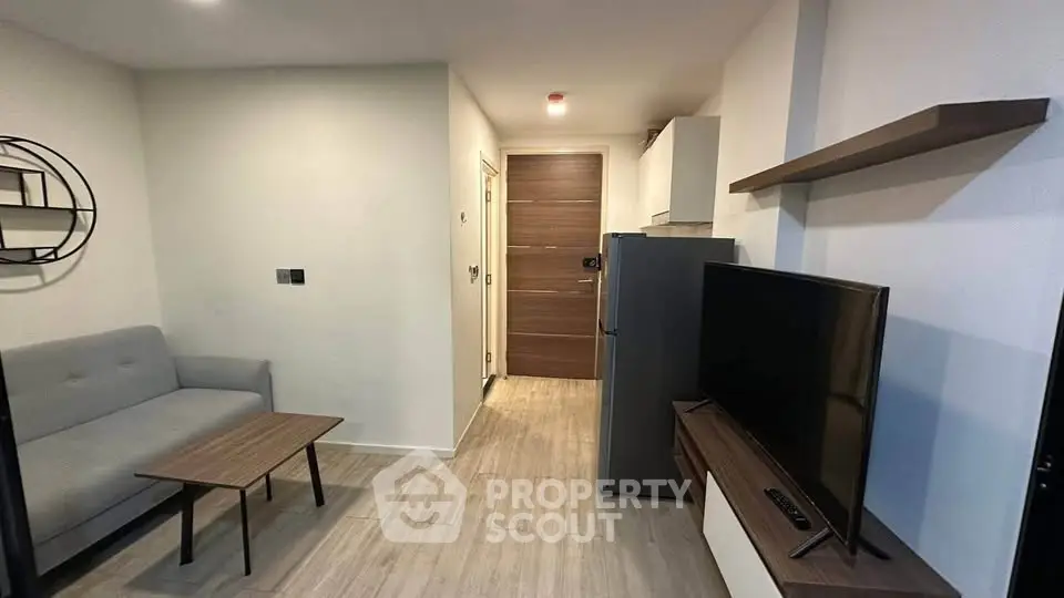 Modern living room with sleek furniture and TV, showcasing minimalist design and neutral tones.