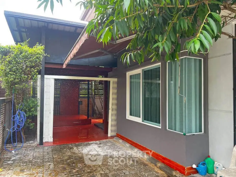 Charming residential exterior with covered carport and lush greenery, perfect for family living.