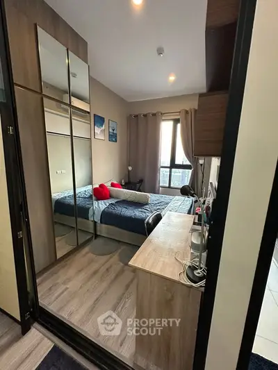 Modern bedroom with mirrored wardrobe and study desk, featuring cozy decor and natural light.