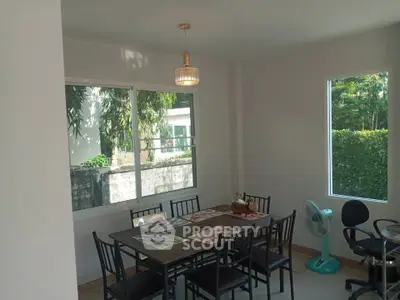 Bright dining area with large windows and modern furniture in a cozy home setting.