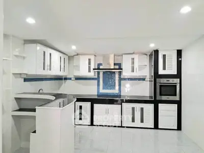 Modern kitchen with sleek white cabinets and built-in oven in a stylish home.