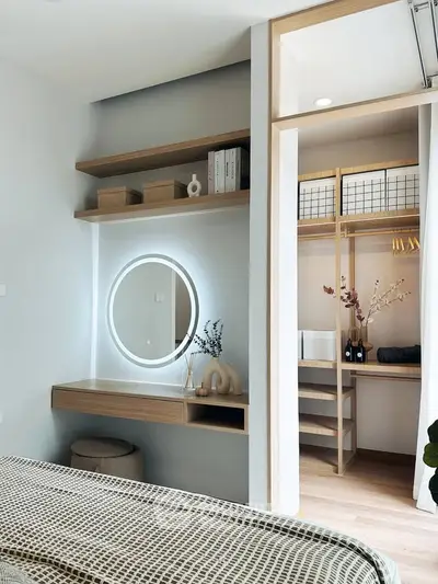 Modern bedroom with stylish vanity and walk-in closet, featuring sleek wooden shelves and contemporary decor.