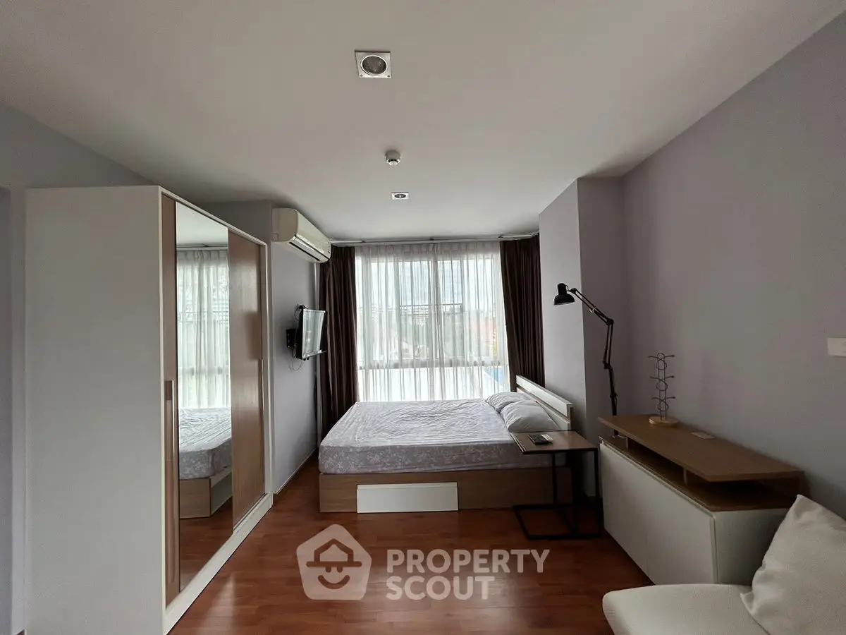 Modern bedroom with large window, wooden floor, and stylish furniture.