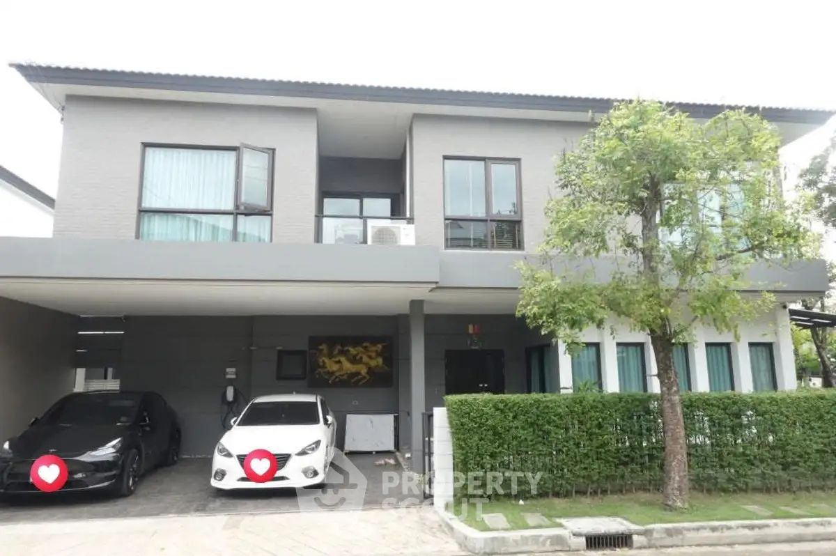 Modern two-story house with carport and lush greenery in a serene neighborhood.