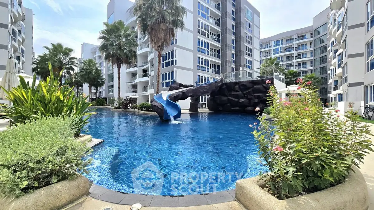 Luxurious apartment complex with stunning pool and slide, surrounded by lush greenery and modern architecture.