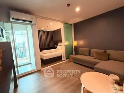 Modern living room with cozy sofa and view of bedroom through glass partition.