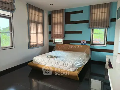 Spacious bedroom with modern decor and large windows offering natural light.