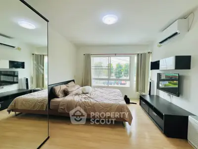 Spacious modern bedroom with large window and mirrored wardrobe in stylish apartment.