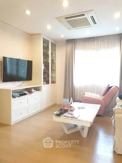 Bright living room with modern decor, wall-mounted TV, and cozy seating area.