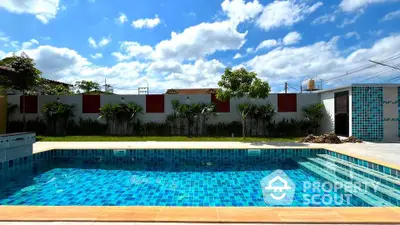 Luxurious outdoor pool with vibrant blue tiles under a clear sky, perfect for relaxation and entertainment.