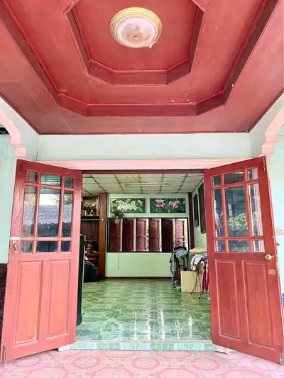 Charming entrance with wooden doors leading to a cozy interior with floral decor and green tiled floor.