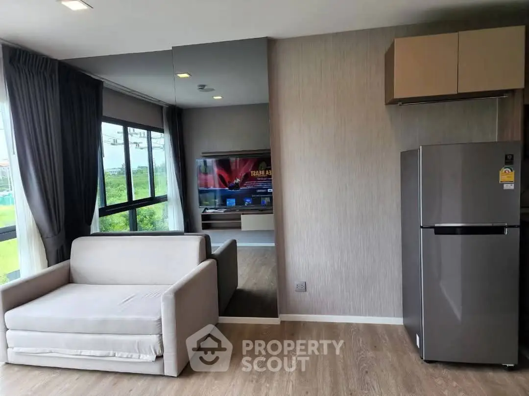 Modern living room with sleek fridge and cozy sofa, large windows offering natural light and scenic views.