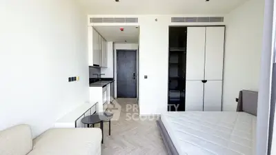 Modern studio apartment with sleek design, featuring a cozy bed, compact kitchen, and stylish furniture.