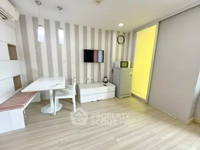 Modern compact living room with dining area, TV, and kitchenette in stylish apartment.