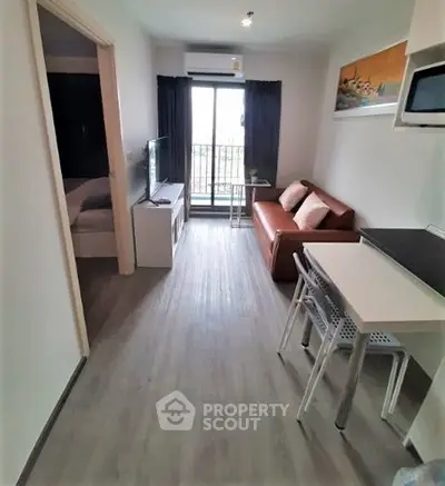 Modern apartment with cozy living room and balcony access, featuring sleek furniture and natural light.