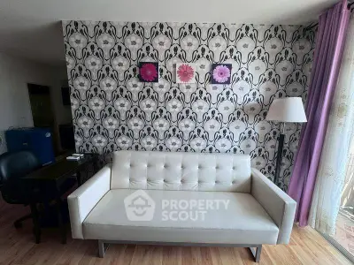 Stylish living room with modern white sofa and floral wallpaper, accented by purple curtains and decor.