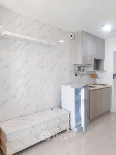Modern kitchen with sleek cabinetry and compact fridge in stylish apartment.