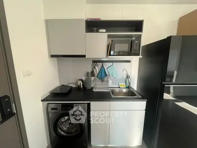 Modern compact kitchen with washing machine and microwave in sleek apartment.