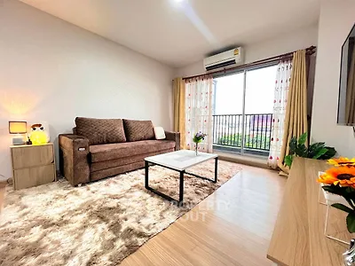 Cozy living room with plush sofa, stylish decor, and large window offering natural light.
