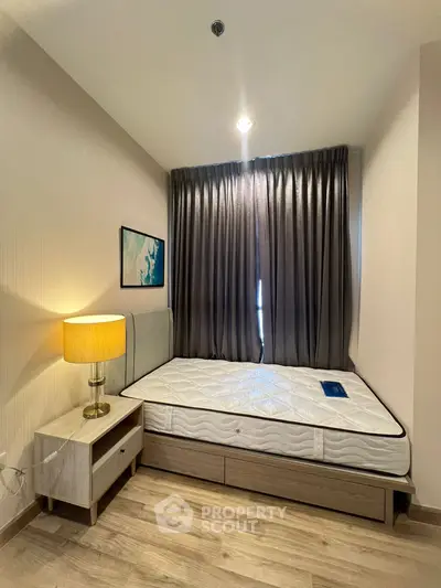 Cozy bedroom with modern decor and natural light, featuring a comfortable bed and stylish lamp.