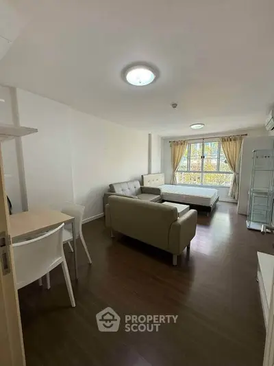 Spacious studio apartment with modern furnishings and large window for natural light.